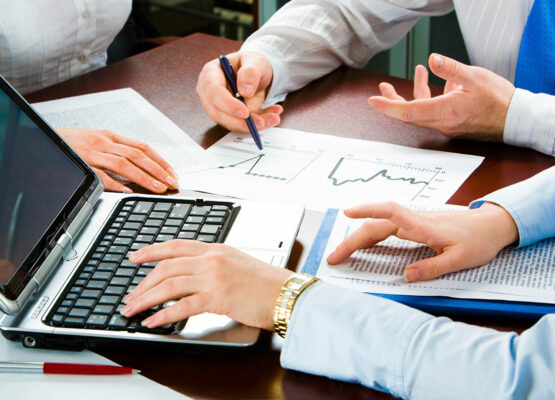 A group of people sitting around a table with papers.